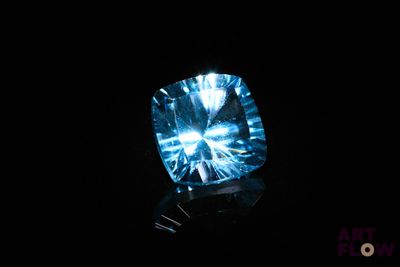 a close up of a blue diamond on a black surface