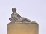 a bronze statue of a woman laying on a box