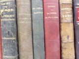 several old books are lined up in a row on a shelf