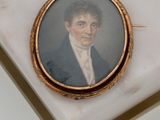 a miniature portrait of a man in a suit on a marble table