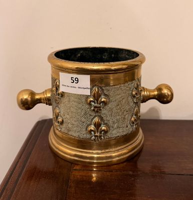 un vase en laiton posé sur une table en bois, avec une étiquette de prix dessus