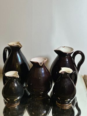 cinq vases posés sur une table en verre avec un miroir