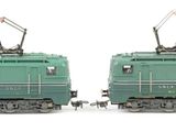 two green trains sitting side by side on a white surface