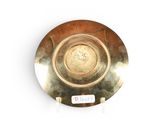 a gold plate on a white surface with a sticker on it
