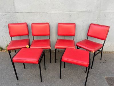 quatre chaises rouges disposées les unes à côté des autres sur une surface en béton