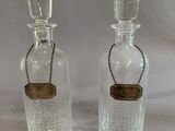 two clear glass bottles with a chain around the neck of them