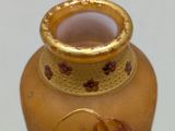 a small vase with a gold rim on a white surface