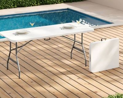 une table installée sur une terrasse en bois près d'une piscine