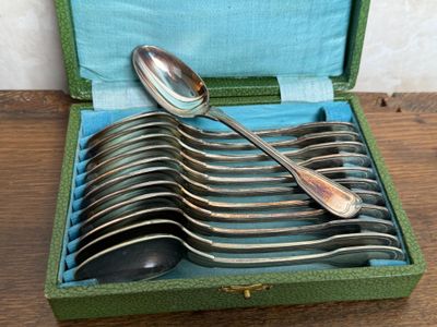 plusieurs cuillères et cuillères à soupe dans un étui vert posé sur une table en bois