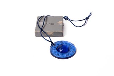 collier composé d'un disque en verre bleu monté sur un cordon et orné d'un livre
