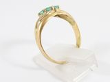 a gold ring with emerald stones on a clear base