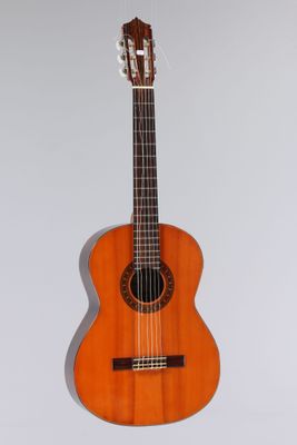 une guitare acoustique orange accrochée à un mur sur fond blanc
