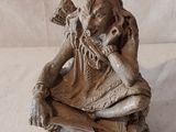 une petite statue représentant une femme assise sur un rocher