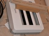 un grille-pain blanc posé sur une boîte en carton, à côté d'une poêle