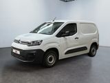 La camionnette blanche est garée dans une grande pièce blanche.