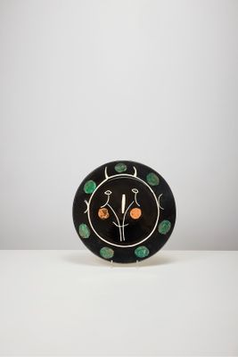 une assiette noire décorée d'oranges et de feuilles