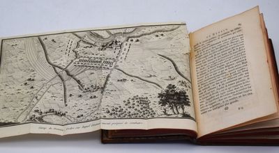 un livre ouvert, sur lequel figure une carte, posé sur une table