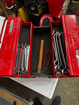 une boîte à outils rouge remplie d'outils, posée sur une table