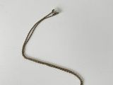 a close up of a necklace on a white surface with a chain