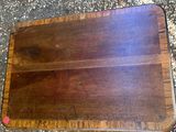 a close up of a wooden cutting board on the ground