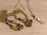 a gold chain with a necklace on it and a small doll on the table
