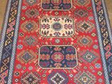a red and blue rug sitting on top of a cement floor