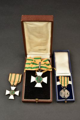 deux médailles et une croix sont rangées dans un écrin posé sur une table
