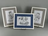 trois dessins encadrés représentant un bébé et un chat posés sur une table