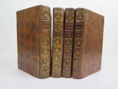 trois vieux livres sont empilés sur une surface blanche