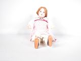 a small doll sitting on a white surface with a white background