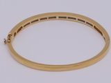 a close up of a gold bang bracelet on a white surface