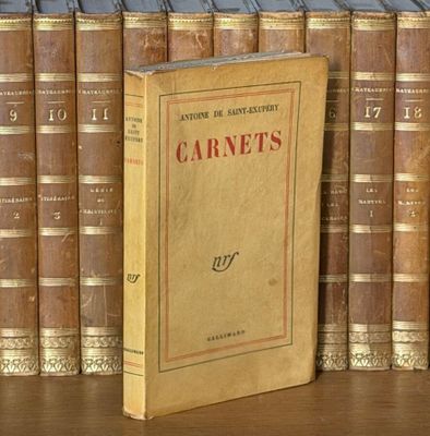 un livre posé sur une table, devant une pile de livres