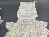 two pairs of white dresses and a hat are on a table