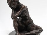 bronze sculpture of a woman sitting on her knees on a black base