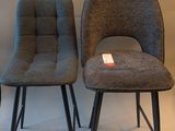 two gray chairs sitting next to each other on a white floor