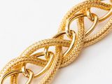 a close up of a gold chain bracelet on a white surface