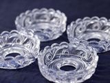 four clear glass bowls with swirl designs on a black surface