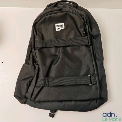 un sac à dos noir posé sur une table à côté d'une tasse