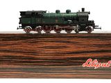 un petit train miniature posé sur un socle en bois, sur fond blanc