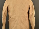 a tan jacket on a mannequin stand against a black background