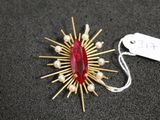 un gros plan sur une broche rouge ornée de perles, avec une étiquette de prix