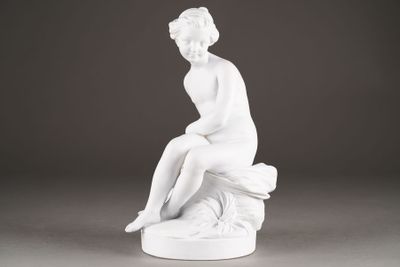 a white statue of a woman sitting on top of a rock