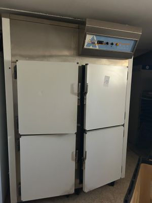 two white refrigerators in a kitchen next to a trash can