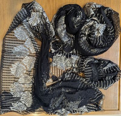 a close up of a black and white scarf on a wooden surface