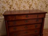 une commode en bois dans une pièce avec du papier peint à motifs floraux