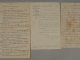two old papers with writing on them sitting on top of a table