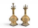 pair of antique brass oil lamps on pedestals on a white background