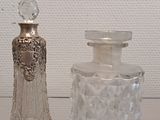 two glass bottles sitting on a glass shelf next to each other