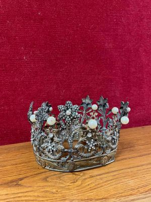 silver metal crown with pearls and flowers on a wooden table