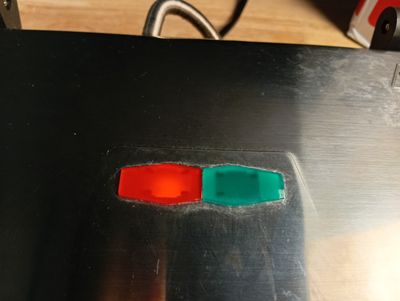 un bouton rouge et un bouton vert posés sur une table en métal
